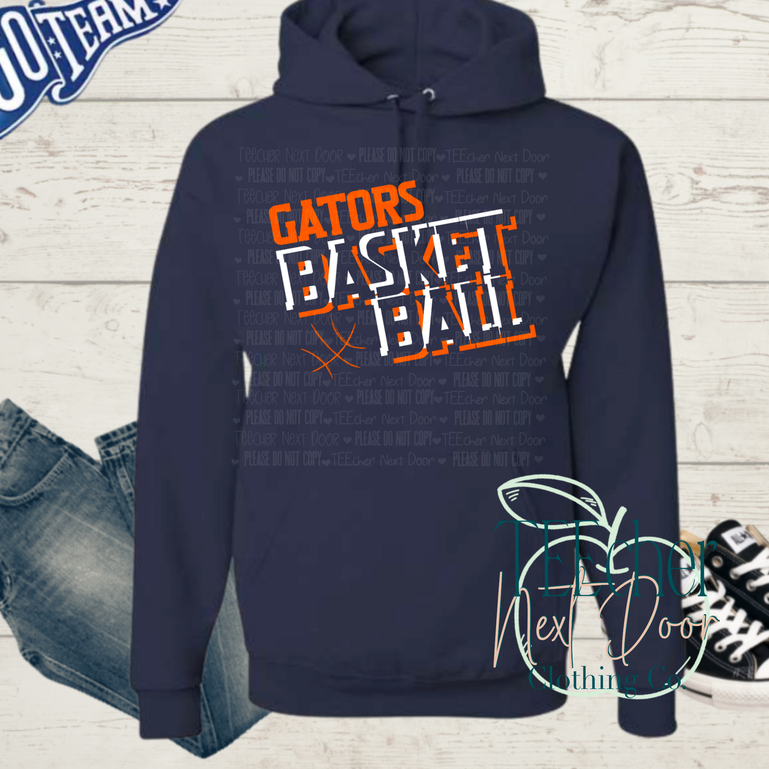 Navy hoodie with 'Gators Basketball' text on a wooden surface with jeans and sneakers.