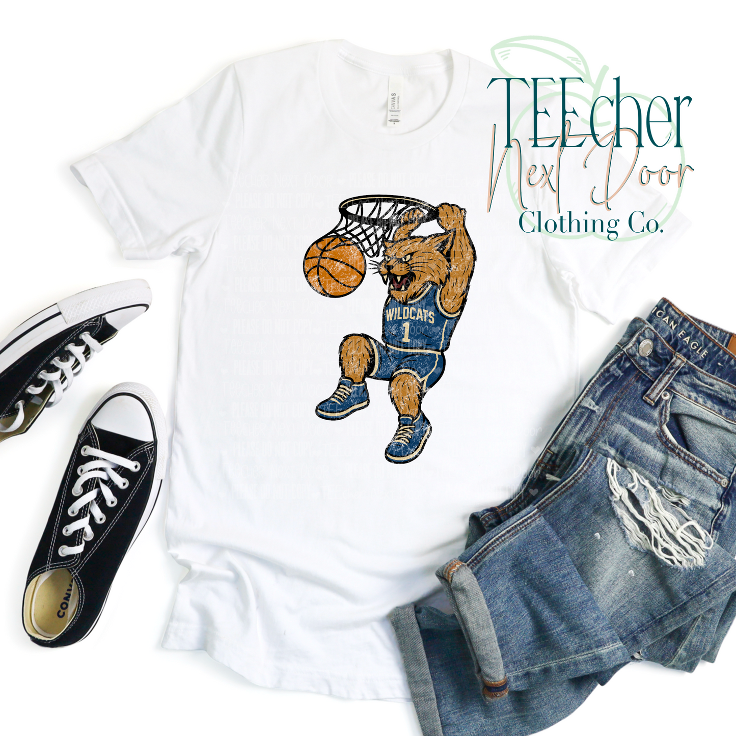 White t-shirt with a cartoon wildcat playing basketball, paired with denim shorts and black sneakers on a white background.